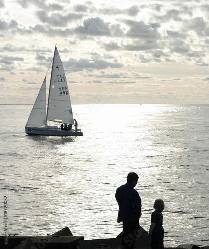 Silhouettes of father and son looking at ships in the see