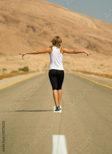 Young girl running over a desert highway.