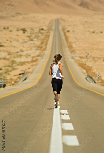 Young girl running over a desert highway.