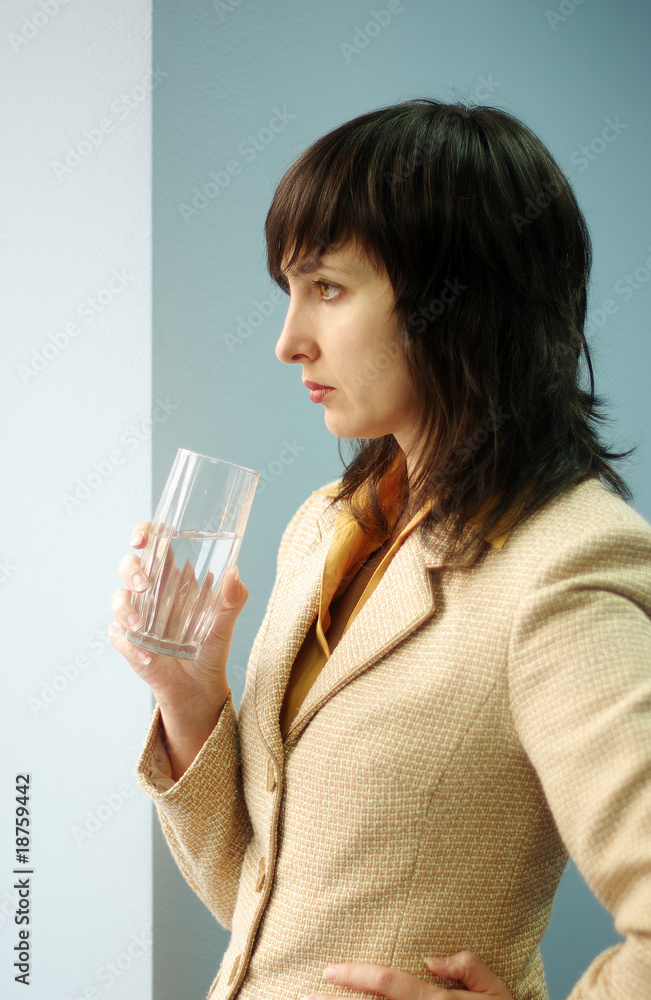 Beautiful brunette woman with glass of water by the window Beautiful brunette woman with glass of water by the window
