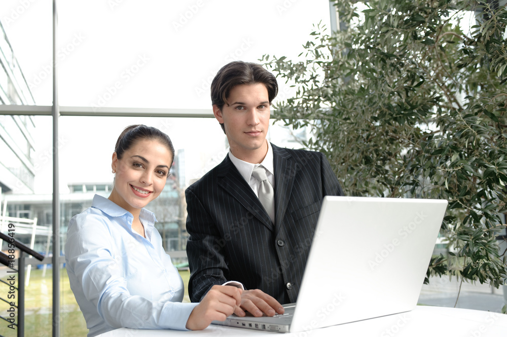 junges business team bespricht sich an tisch mit laptop in büro junges business team bespricht sich an tisch mit laptop in büro