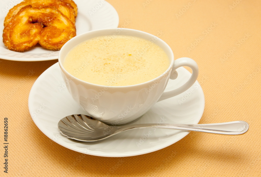 Closeup of coffee with milk in white cup and a palmier pastry Closeup of coffee with milk in white cup and a palmier pastry