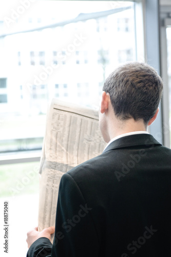 geschäftsmann liest zeitung in bürogebäude,von hinten