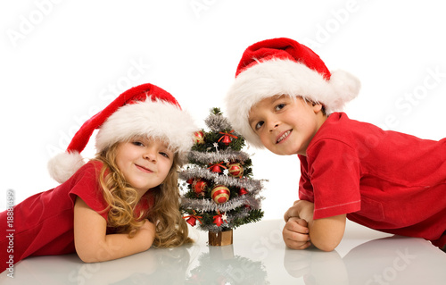 Happy kids with santa hats and small christmas tree