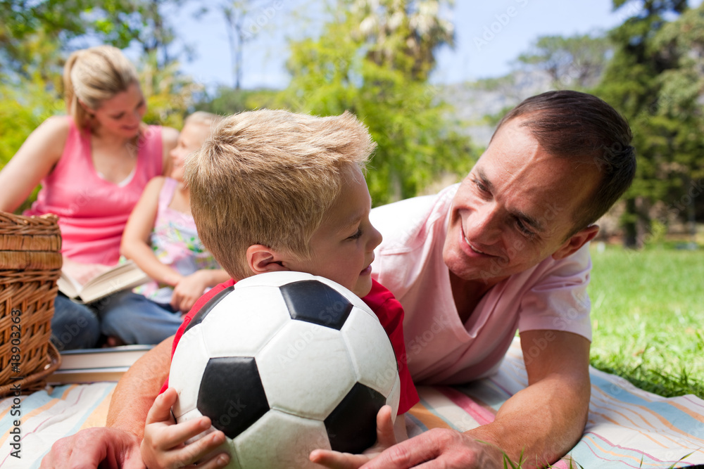 Father and son holding a soccer ball with their family reading i Father and son holding a soccer ball with their family reading i