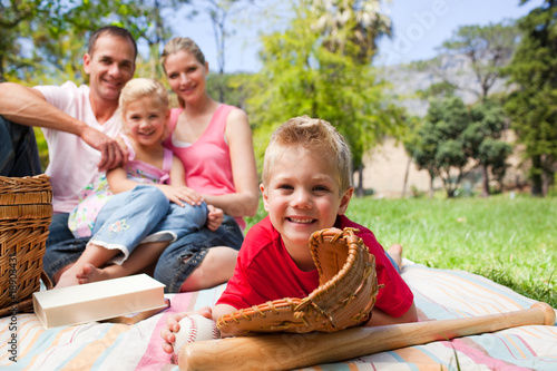Photography Smiling little boy wearing a baseball glove while having a picni