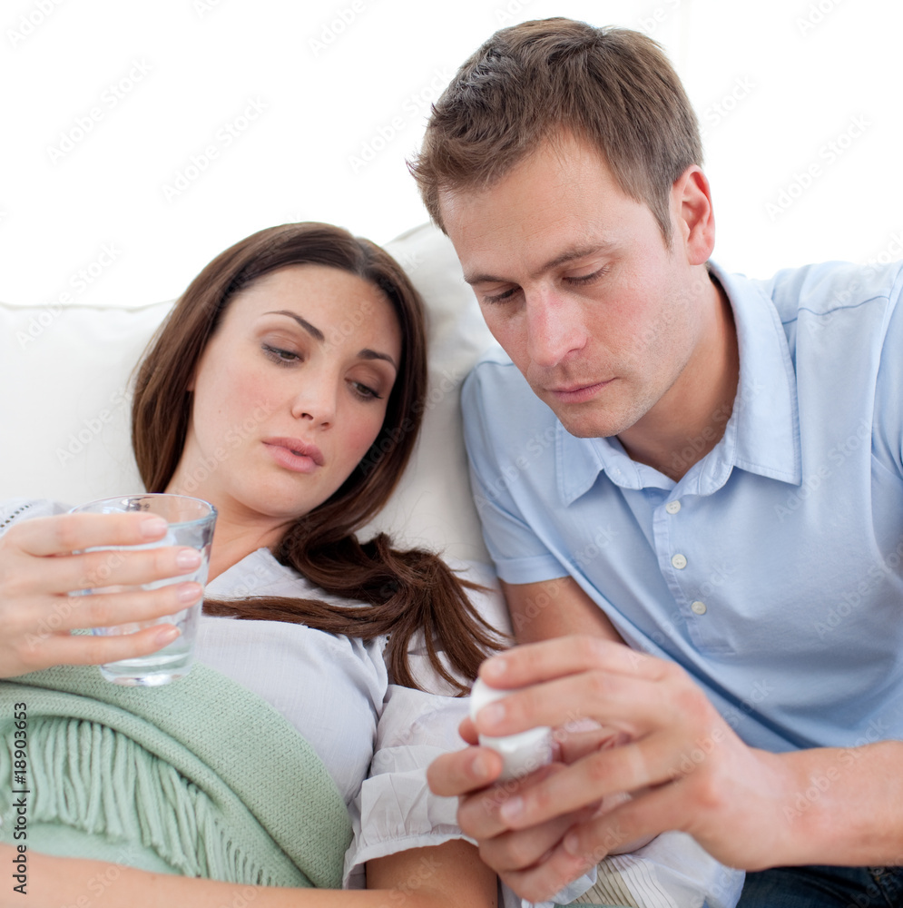 Husband giving pills to his wife with the flu Husband giving pills to his wife with the flu