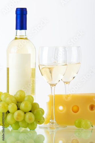 Bottle of white wine  wine glasses  cheese and grape