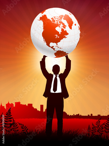 Businessman holding up globe on sunset background