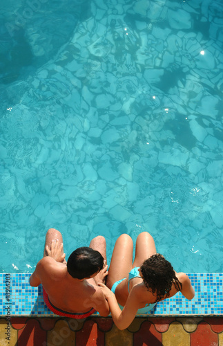 Young pair sits beside water pool