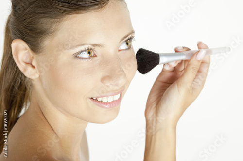 portrait of young woman putting on face powder