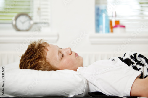 Boy sleeping on his back in bed