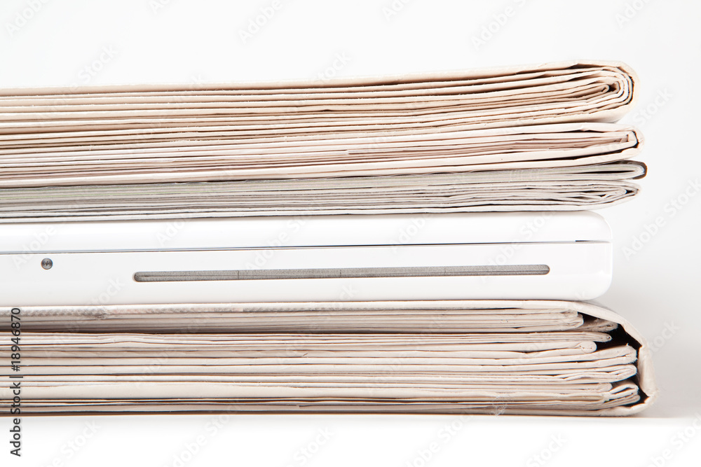Zeitungsstapel mit Laptop dazwischen Zeitungsstapel mit Laptop dazwischen