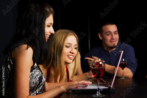 Young friends with laptop in a bar.