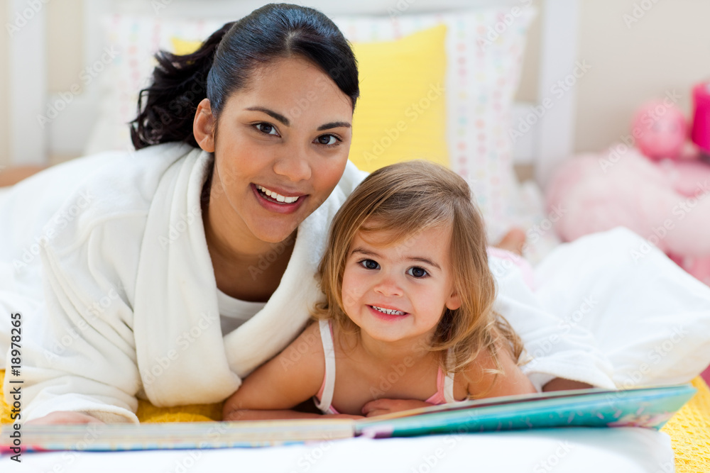 Portrait of a smiling mother and her daughter reading together Portrait of a smiling mother and her daughter reading together