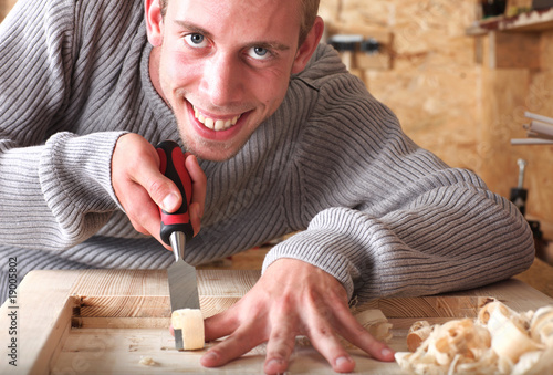 Young carpenter with gad working and smiling