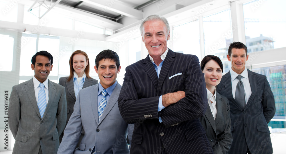 Senior manager with folded arms accompanied by his team Senior manager with folded arms accompanied by his team
