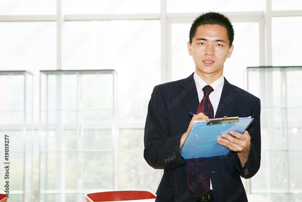 young asian businessman sitting on desk in office young asian businessman sitting on desk in office