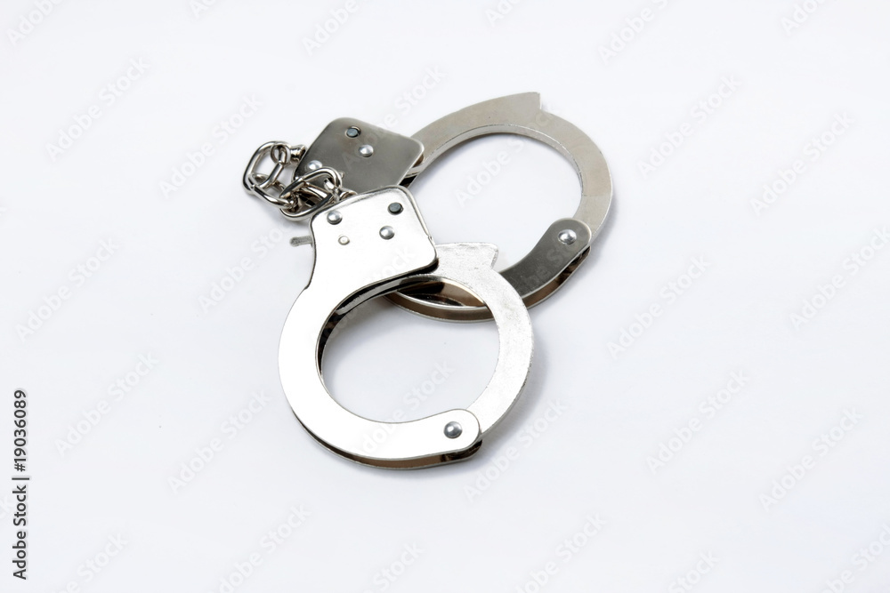 Pair of handcuffs isolated on a gray background.. Pair of handcuffs isolated on a gray background..