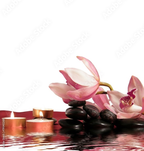 Orchid,pebbles,candles and silk with reflection in water.