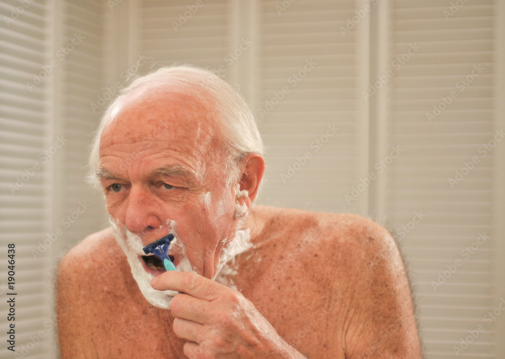 Elderly man shaving in front of a mirror Elderly man shaving in front of a mirror
