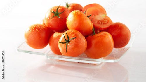 dojrzale czerwone pomidory na talerzu, na białym tle, mokre
