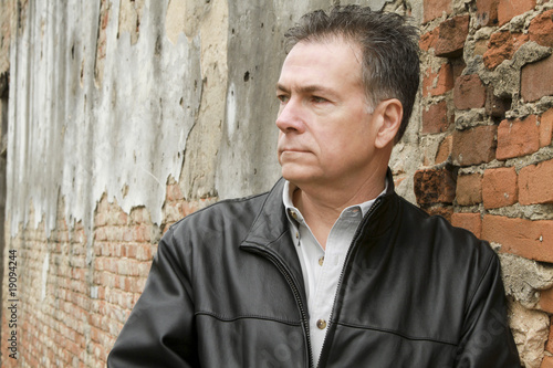 A man leaning up against an old brick wall.