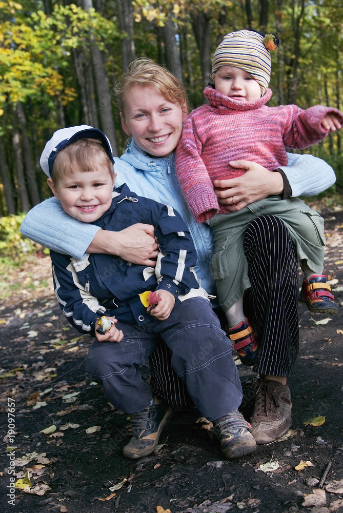 Happy family of mother and two sons in autumn forest Happy family of mother and two sons in autumn forest