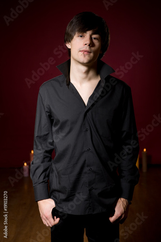 Young  man in black shirt on red background with candles photo