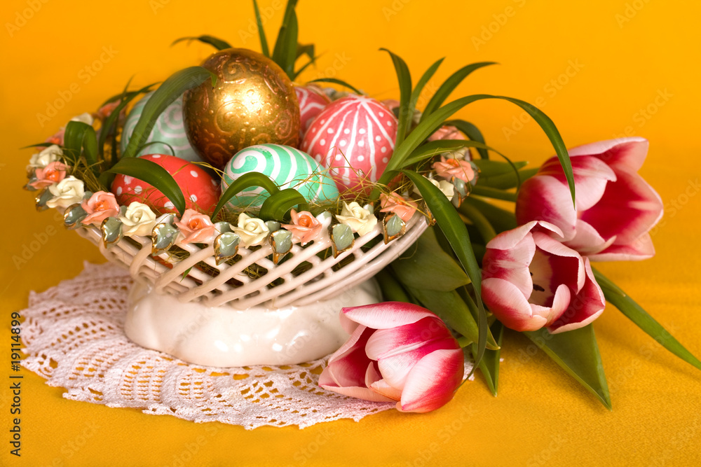 Easter colored eggs and pink tulips in a porcelain basket Easter colored eggs and pink tulips in a porcelain basket