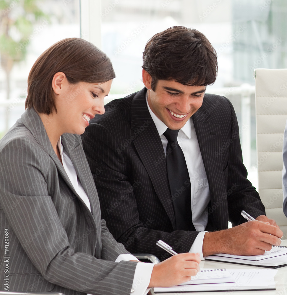 Two smiling colleagues studying sales report with their team Two smiling colleagues studying sales report with their team