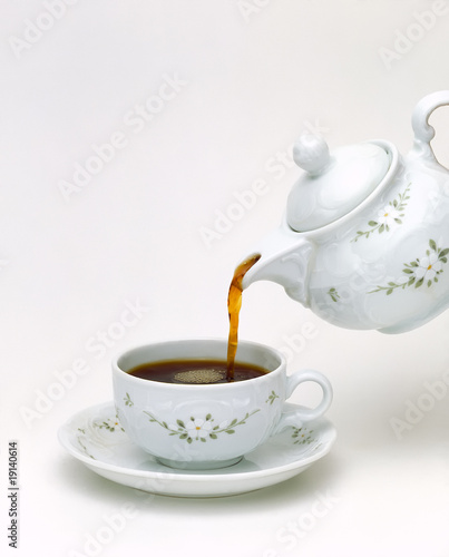 white porcelain teapot pouring black tea isolated on white background