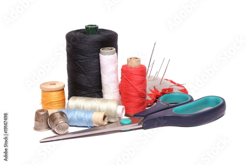 Scissors, needles and spools isolated over white.