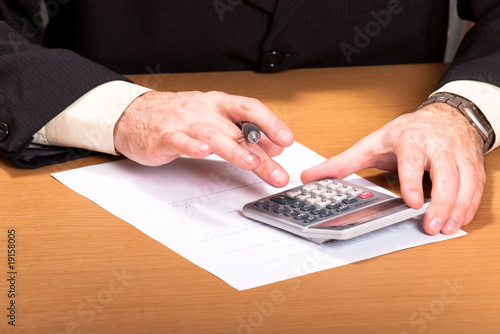 man hand holding pen on calculator buttons in office