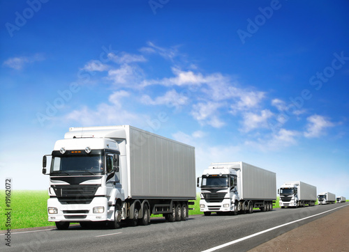 caravan of white trucks on highway under blue sky