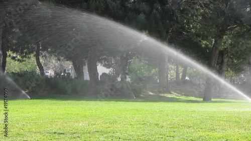 Water sprinkler showering grass in park