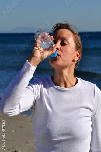 Woman drinking water at the beach