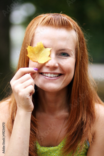 Smiling woman with an autumn leaf