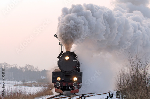 Retro steam train starting from the station during wintertime