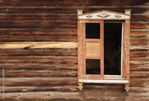 Wall of an old wooden house and the lop-sided window