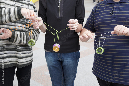 three teens with yo-yo toys in their hands. focus on yo-yo
