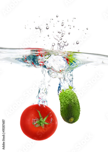 red tomato and green cucumber dropped into water