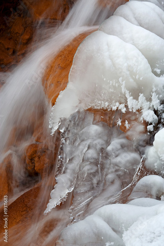 Winer waterfall. Snow, ice, red stones.