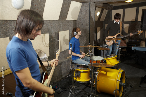 rock band. two guitarists and drummer working in studio