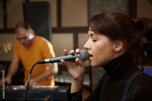 vocalist girl in studio. keyboard player in out of focus