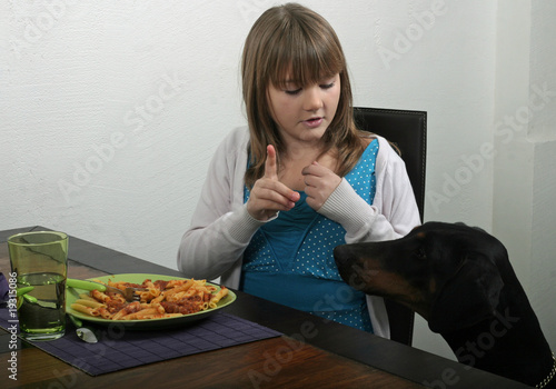 jeune fille éduquant son chien à ne pas réclamer à table photo