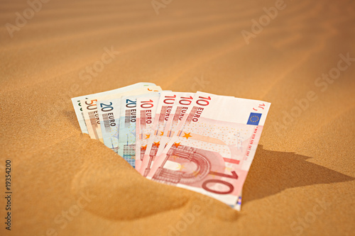 setting money into sand - german phrase