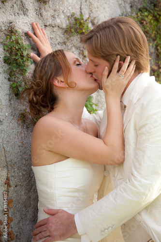 bride and groom kissing at wall