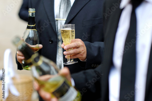 Groom holding bottle and glasses of shampagne photo