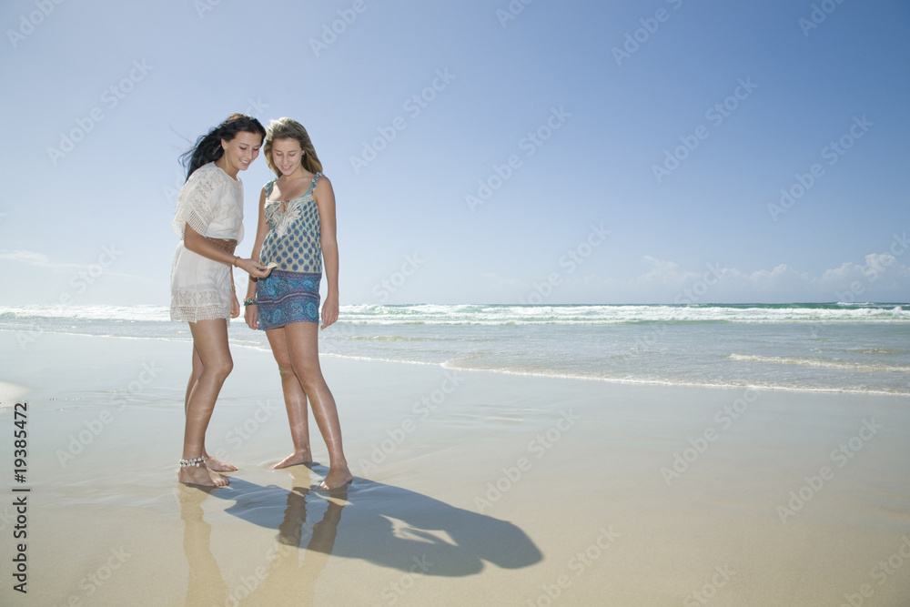 sisters looking at shell on beach